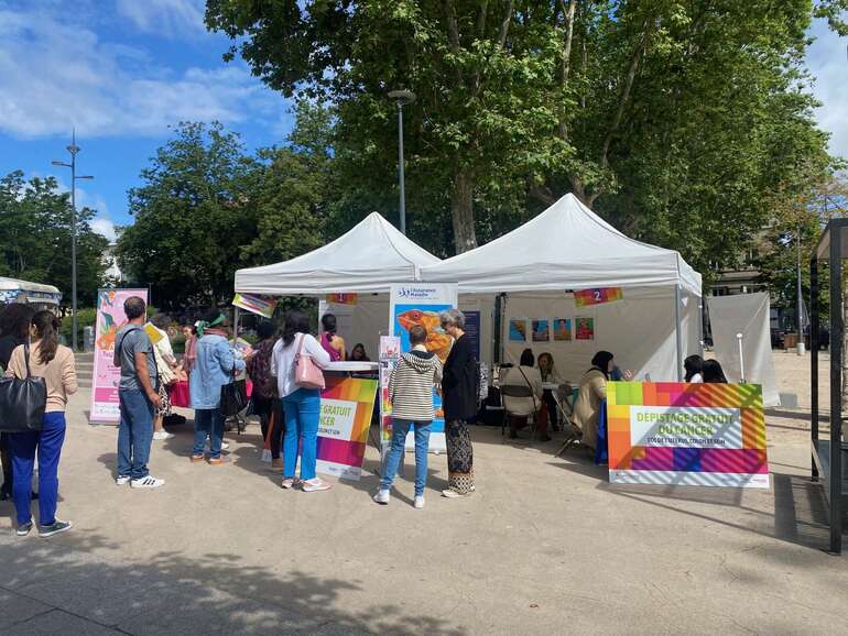 un groupe de personnes devant des chapiteaux où est mentionné "dépistage gratuit du cancer"
