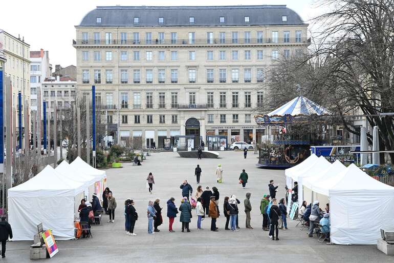 une place avec des stands occupés par de nombreuses personnes