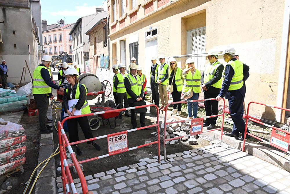 un groupe qui visite une rue en chantier (pose de pavés)