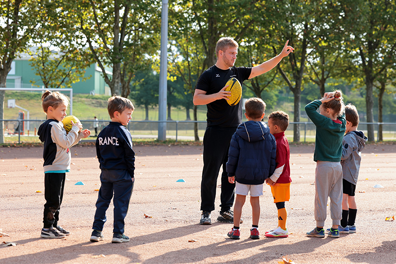 groupe d'enfants avec un homme qui tient un ballon de rugby