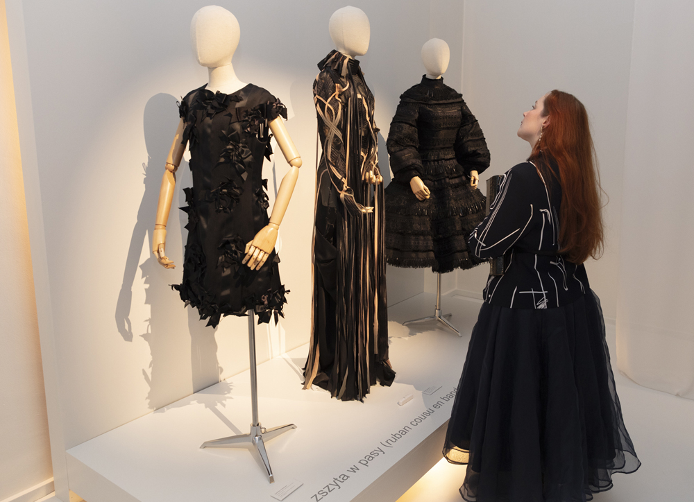 une femme qui observe 3 robes de haute couture