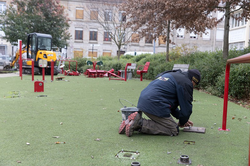 un homme travaillant sur la réparation d'agrès dans un parc urbain