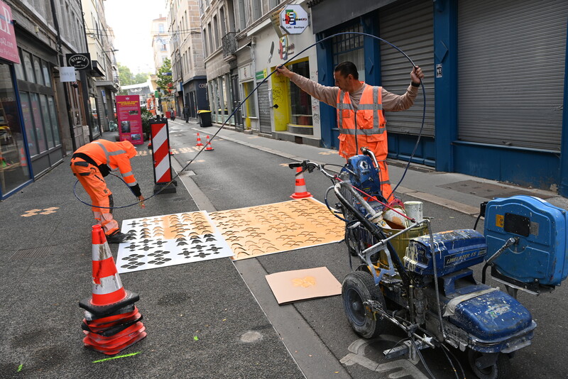 deux ouvriers qui font du marquage au sol orange sur une rue