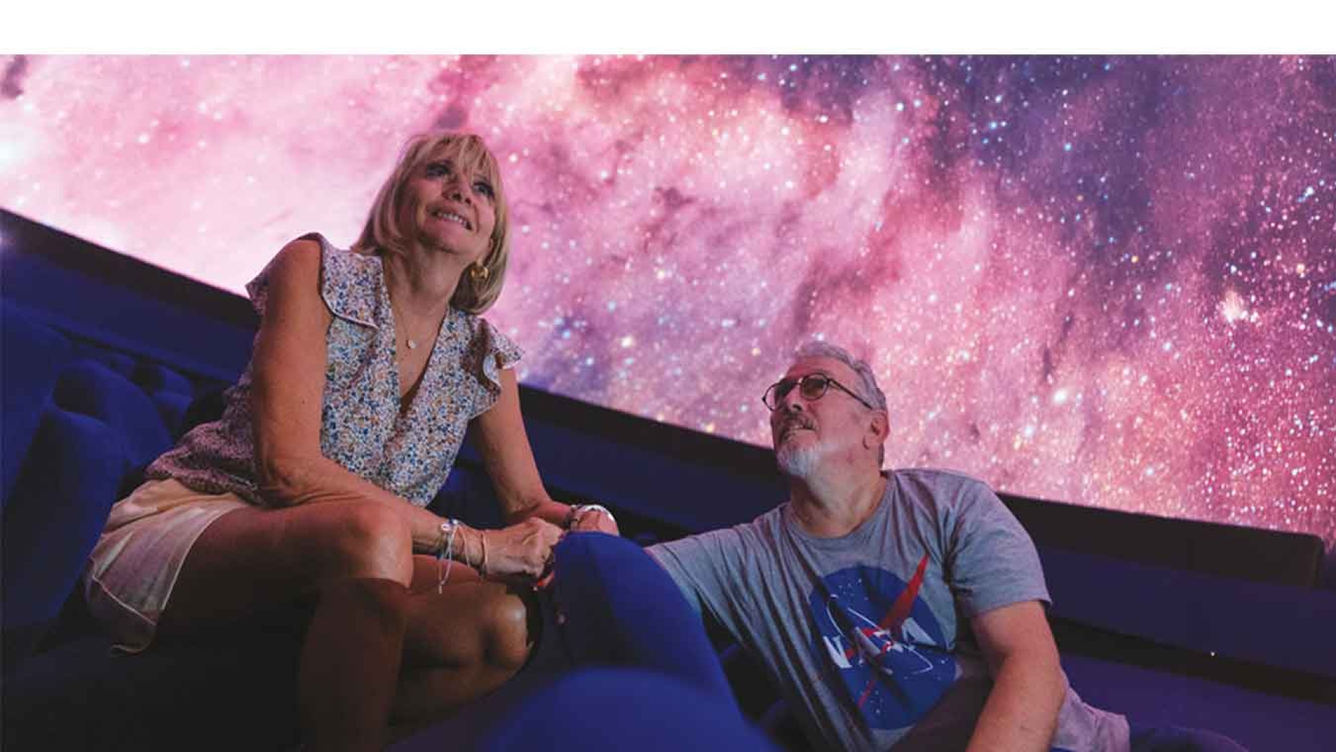 un homme et une femme lèvent les yeux pour regarder l'univers dans un planétarium