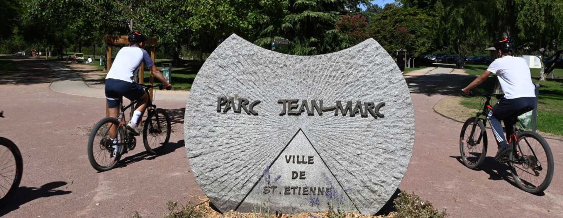 vététistes passant devant la stèle "Parc Jean-Marc"