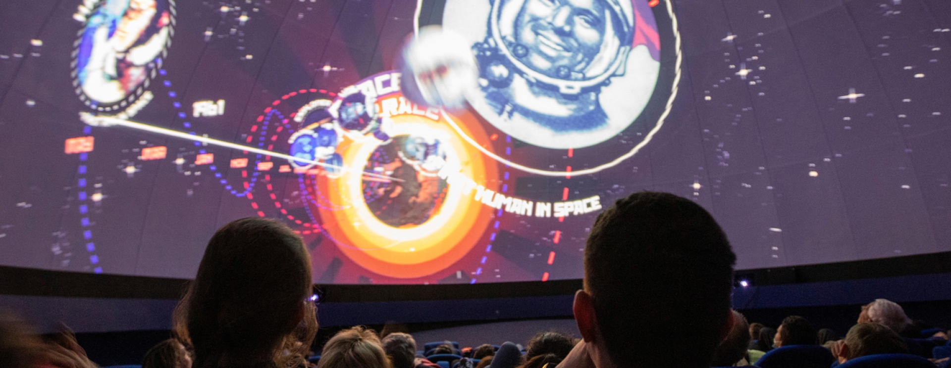 un groupe qui regarde une écran géant avec des planètes