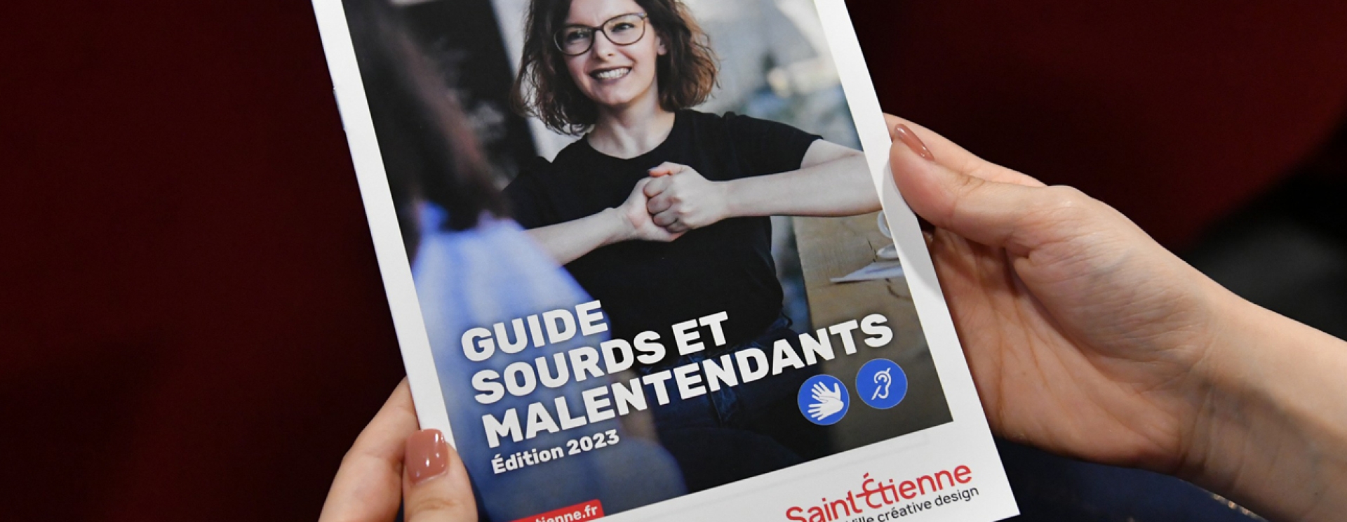 une personne qui a dans les mains le guide handicap sourds et malentendants