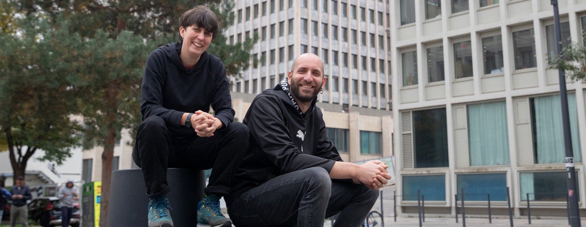 une homme et une femme assis qui posent devant un bâtiment