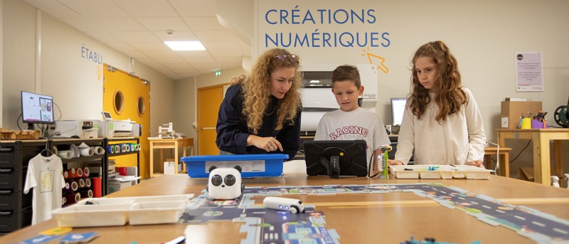 une femme et deux enfants dans une salle dédié aux créations numériques - Agrandir l'image, fenêtre modale