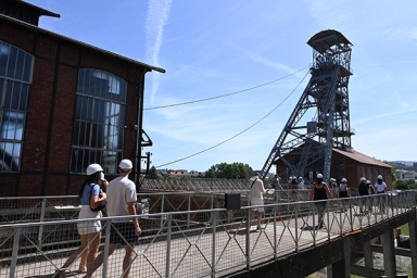 des personnes qui marchent sur une passerelle, un chevalement en arrière plan
