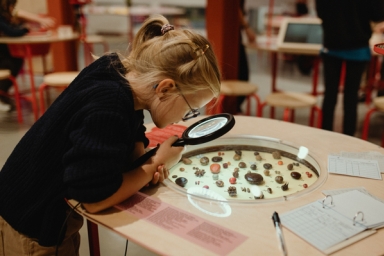 une jeune fille regarde des graines avec une loupe