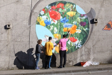 Plusieurs personnes qui peignent un dessin fleuri sur un mur
