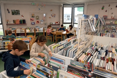 plusieurs enfants qui lisent et choisissent des livres dans une médiathèque