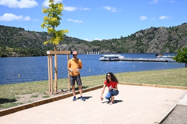 un homme et une femme qui jouent à la pétanque avec un fleuve en arrière plan