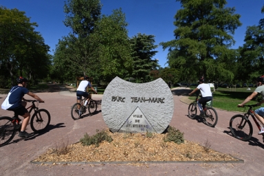 Cyclistes à côté de la stèle du parc Jean-Marc