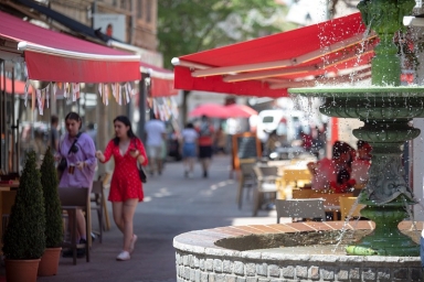 rue piétonne avec fontaine à eau et deux femmes en robe d'été