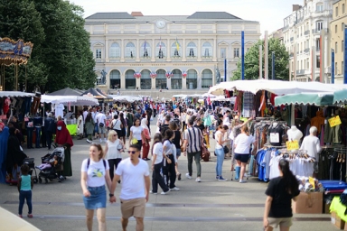 une foule de personnes déambulant entre des stands, sur une place