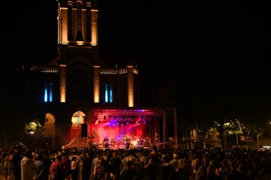une foule devant un concert, une cathédrale en arrière-plan