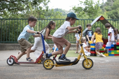enfants sur des trotinettes dans une cour d'école