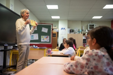 Un homme lit une histoire à des élèves d'école primaire