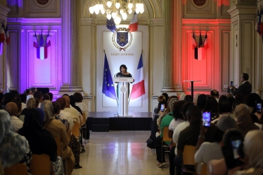 une assemblée assise, une femme au pupitre 