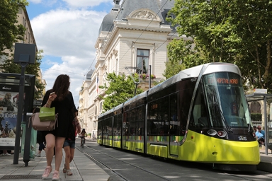 un tramway jaune et noir et des piétons sur le côté