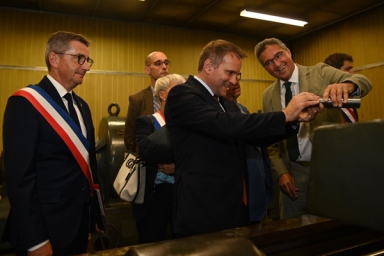 Le maire au côté du Ministre qui inspecte une pièce en métal dans une entreprise