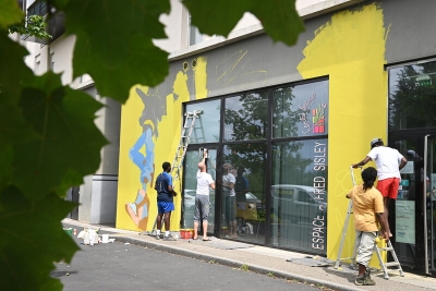 un groupe qui peint la façade d'un bâtiment en jaune - Agrandir l'image 2 sur 3, fenêtre modale