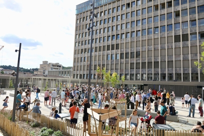 place avec du monde, quelques arbres et un grand immeuble en arrière plan - Agrandir l'image, fenêtre modale