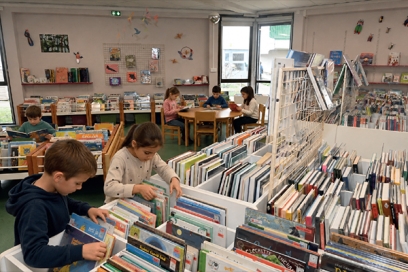 plusieurs enfants qui lisent et choisissent des livres dans une médiathèque - Agrandir l'image, fenêtre modale