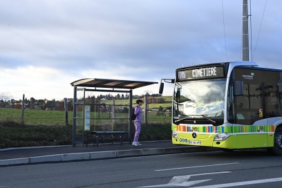 un jeune homme à un quai de bus avec un bus en approche - Agrandir l'image, fenêtre modale