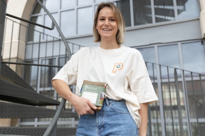 portrait d'une femme souriant qui tient un paquet avec la mention "Ptitcul" - Agrandir l'image, fenêtre modale