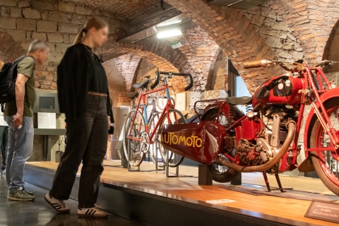 ancienne moto et ancien vélo exposés devant un groupe de personnes