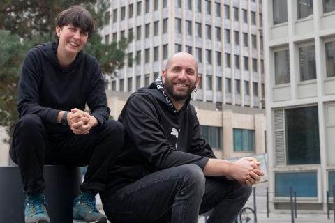 une homme et une femme assis qui posent devant un bâtiment
