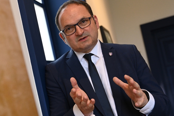 un homme en costume debout qui parle avec ses mains - Agrandir l'image, fenêtre modale